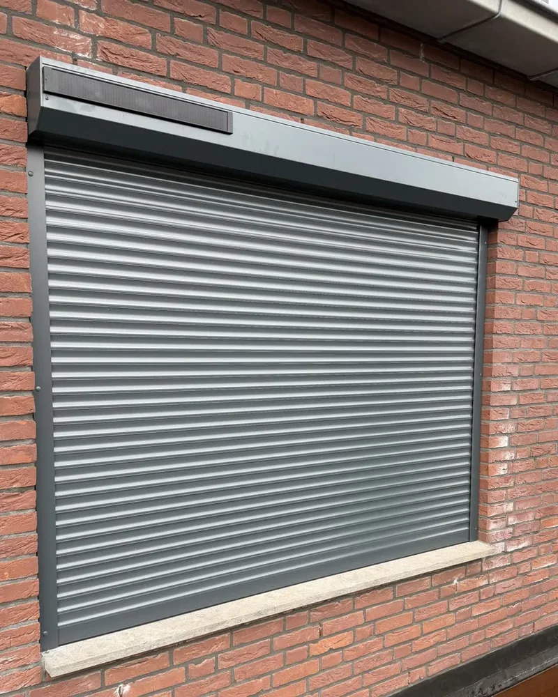 Gesloten grijs solar rolluik aan een bakstenen gevel