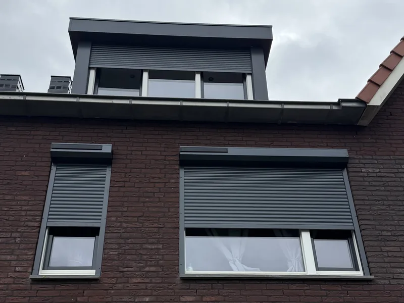 Antraciet rolluiken aan een bakstenen woning, werk van Bas bij RolluikBroers